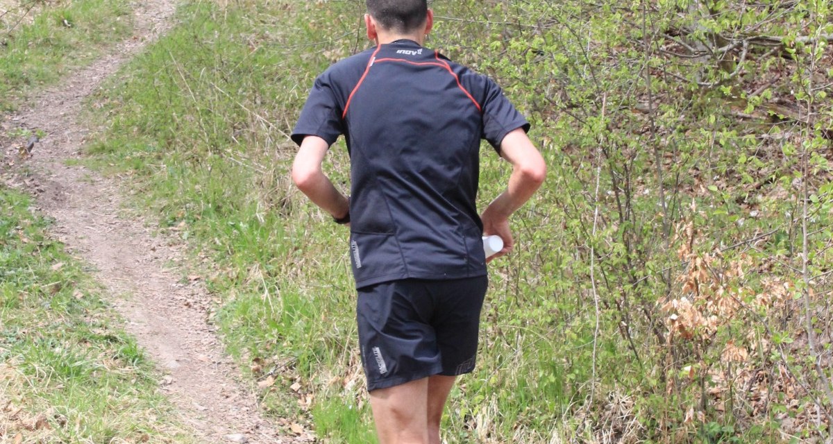 Ein Trailläufer in schwarzer Sportkleidung joggt auf einem schmalen Pfad durch einen grünen Wald., © Natur.Nah. Schönbuch & Heckengäu