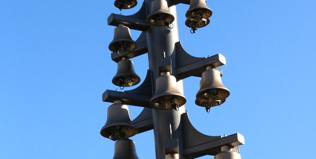 Ein Glockenspiel mit mehreren Glocken an einem Metallpfosten vor einem klaren blauen Himmel., © Bad Urach Tourismus