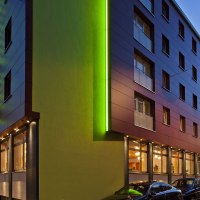 Moderne Hotelaußenansicht bei Dämmerung, mit grüner Beleuchtung und parkenden Autos. Der Schriftzug 'Hotel Wartburg' ist sichtbar., © VCH Hotel Wartburg Moderne Hotelaußenansicht bei Dämmerung, mit grüner Beleuchtung und parkenden Autos. Der Schriftzug 'Hotel Wartburg' ist sichtbar., © VCH Hotel Wartburg