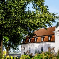 Ein historisches Gebäude mit rotem Dach und weißen Wänden, umgeben von grünen Bäumen und Pflanzen, unter einem klaren blauen Himmel., © DLA Marbach (Anja Bleeser) Ein historisches Gebäude mit rotem Dach und weißen Wänden, umgeben von grünen Bäumen und Pflanzen, unter einem klaren blauen Himmel., © DLA Marbach (Anja Bleeser)