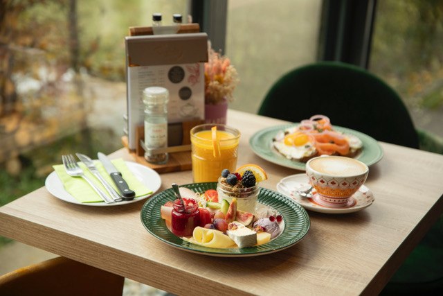 Ein reich gedeckter Frühstückstisch mit Obst, Orangensaft, Kaffee und einem Teller mit Eiern und Lachs., © Ingrid Glückswelt Ein reich gedeckter Frühstückstisch mit Obst, Orangensaft, Kaffee und einem Teller mit Eiern und Lachs., © Ingrid Glückswelt