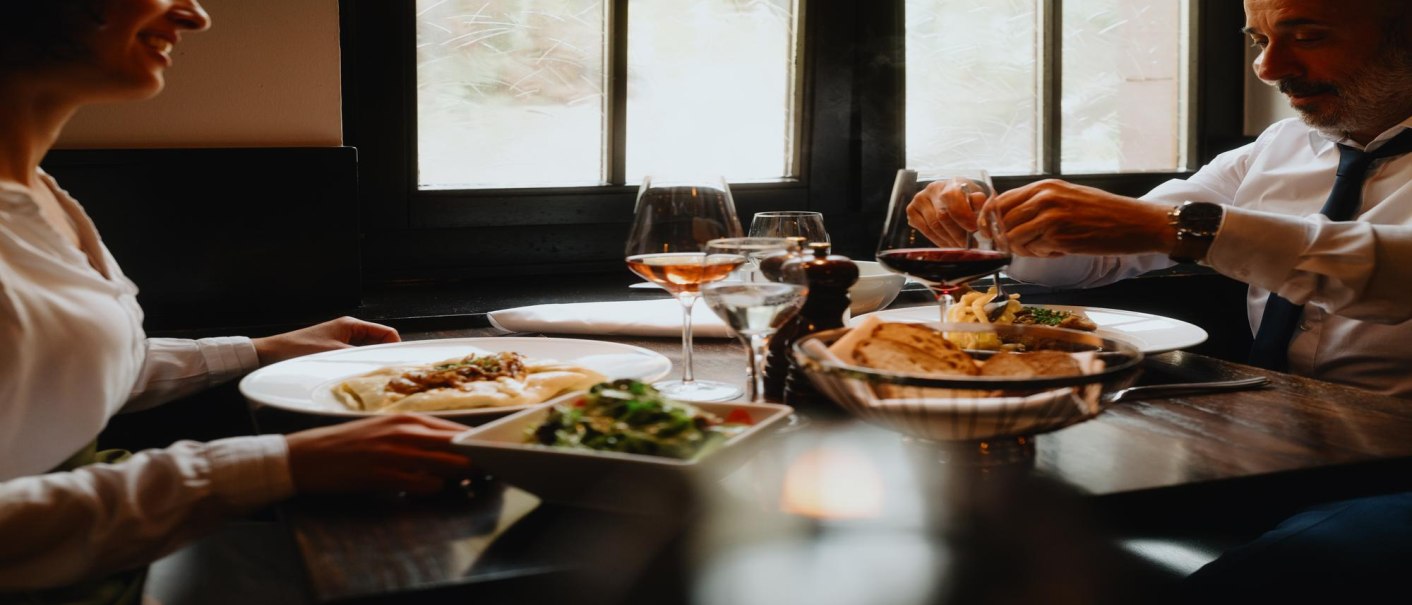 Zwei Personen genießen ein Essen in einem Restaurant. Auf dem Tisch stehen Wein, Brot und Salat. Die Atmosphäre wirkt gemütlich und elegant., © Stuttgart-Marketing GmbH, Alwin Maigler