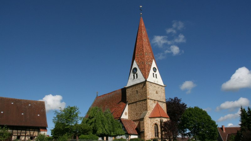 Die Johanneskirche in Gingen steht unter einem klaren blauen Himmel mit vereinzelten Wolken. Umgeben von Bäumen und traditionellen Gebäuden., © Landkreis Göppingen
