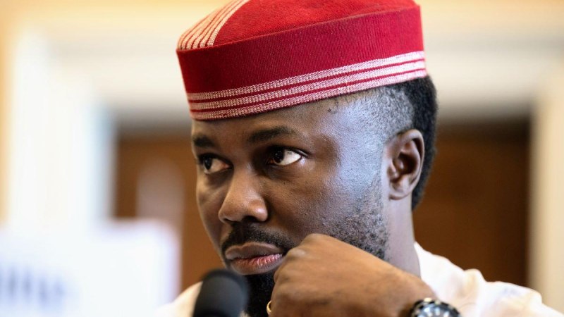 Ein Mann tr&auml;gt eine rote traditionelle Kappe und schaut nachdenklich. Er hat einen Bart und tr&auml;gt eine Uhr. Im Hintergrund ist ein unscharfer Raum zu sehen., &copy; Philip Obaji Jr., mit freundlicher Genehmigung der U.S. Helsinki Commission