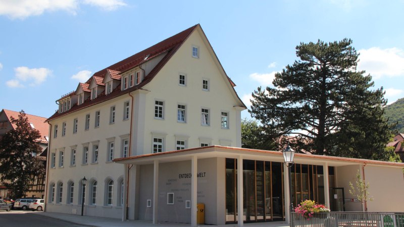 Ein modernes Gebäude mit großen Fenstern und traditionellem Dach, umgeben von Bäumen. Der Himmel ist klar und blau. Ein modernes Gebäude mit großen Fenstern und traditionellem Dach, umgeben von Bäumen. Der Himmel ist klar und blau.