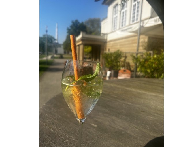 Ein Glas mit einem Getränk, garniert mit Minze und Zimtstange, steht auf einem Tisch im Freien vor einem Gebäude., © Cool-Tours StattReisen Ein Glas mit einem Getränk, garniert mit Minze und Zimtstange, steht auf einem Tisch im Freien vor einem Gebäude., © Cool-Tours StattReisen