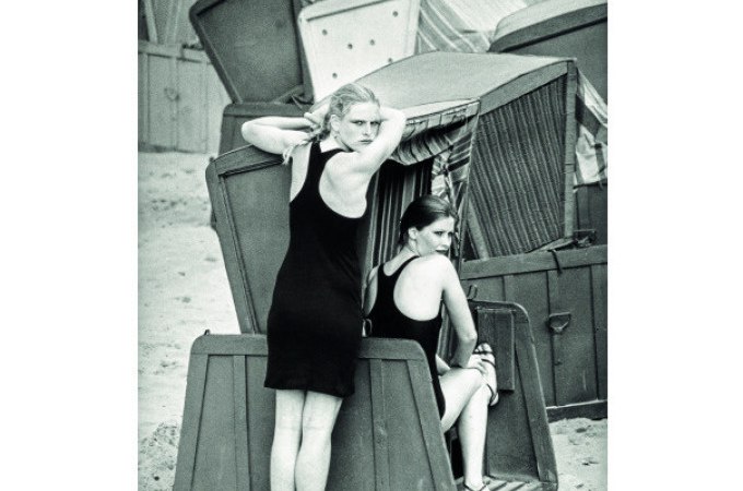 Zwei Frauen in Badeanzügen an einem Strand, eine steht und die andere sitzt in Strandkörben. Im Hintergrund sind weitere Strandkörbe zu sehen., © Kunsthalle Göppingen Zwei Frauen in Badeanzügen an einem Strand, eine steht und die andere sitzt in Strandkörben. Im Hintergrund sind weitere Strandkörbe zu sehen., © Kunsthalle Göppingen