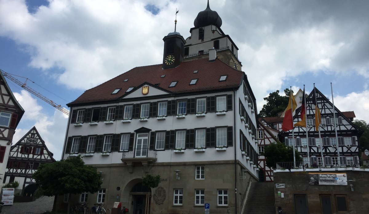Das Rathaus von Herrenberg mit Fachwerkhäusern im Hintergrund. Vor dem Gebäude stehen leere Stühle. Der Himmel ist bewölkt., © www.pro-cycl.de Das Rathaus von Herrenberg mit Fachwerkhäusern im Hintergrund. Vor dem Gebäude stehen leere Stühle. Der Himmel ist bewölkt., © www.pro-cycl.de