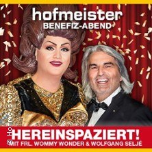 Zwei Personen vor einem roten Vorhang mit Konfetti. Eine tr&auml;gt ein glamour&ouml;ses Kleid, die andere einen Anzug. Text: 'hofmeister Benefiz-Abend'., &copy; links im Bild