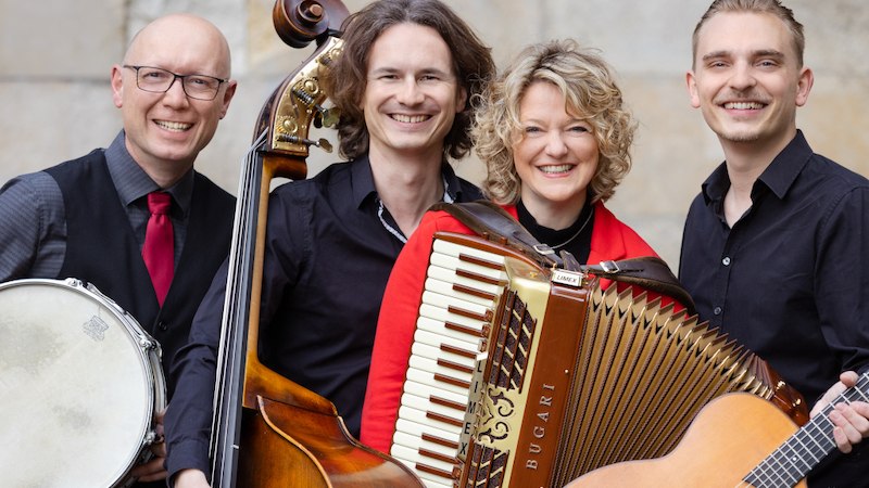 Vier Musiker mit Akkordeon, Kontrabass, Gitarre und Trommel l&auml;cheln in die Kamera. Sie tragen elegante Kleidung. &copy; Christoph Mitterm&uuml;ller, &copy; Kultur- und Sportamt Stadt Bietigheim-Bissingen