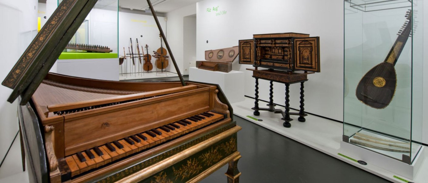Ein Museumsausstellungsraum mit historischen Musikinstrumenten, darunter ein Cembalo, eine Laute und Streichinstrumente in Vitrinen., © Landesmuseum Württemberg