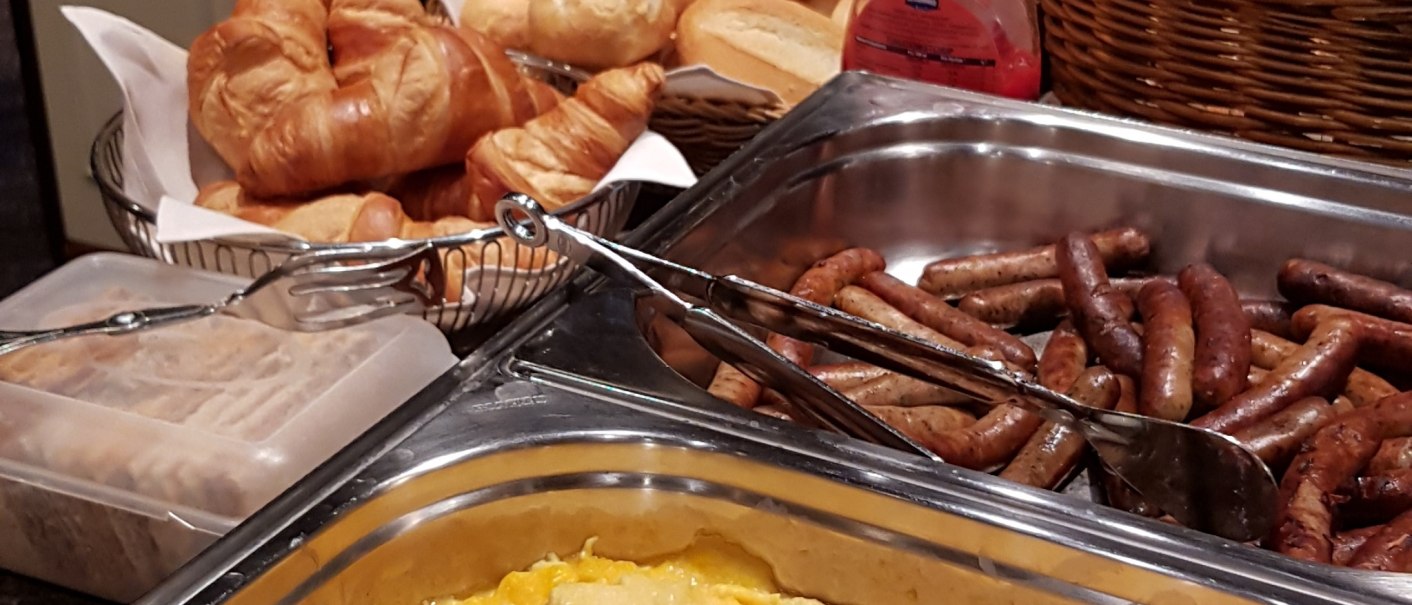 Ein Frühstücksbuffet mit Rührei, Würstchen, Brötchen und Croissants in einem gemütlichen Hotelrestaurant., © Hotel Spahr Ein Frühstücksbuffet mit Rührei, Würstchen, Brötchen und Croissants in einem gemütlichen Hotelrestaurant., © Hotel Spahr