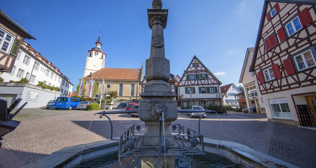 Der Marktbrunnen in Waldenbuch, umgeben von Fachwerkhäusern und einer Kirche im Hintergrund, bei klarem Himmel., © Region Stuttgart Der Marktbrunnen in Waldenbuch, umgeben von Fachwerkhäusern und einer Kirche im Hintergrund, bei klarem Himmel., © Region Stuttgart