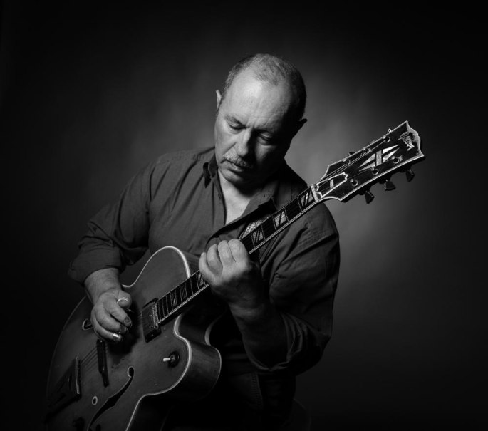 Ein Mann spielt konzentriert auf einer Gitarre. Das Bild ist in Schwarz-Weiß gehalten und zeigt eine ruhige, fokussierte Atmosphäre., © Foto Manfred Pollert Ein Mann spielt konzentriert auf einer Gitarre. Das Bild ist in Schwarz-Weiß gehalten und zeigt eine ruhige, fokussierte Atmosphäre., © Foto Manfred Pollert
