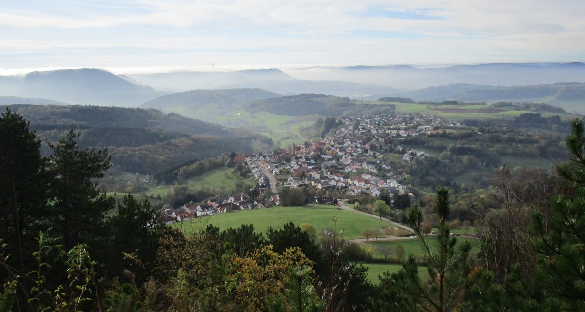 Panoramablick auf ein Dorf in einer h&uuml;geligen Landschaft, umgeben von W&auml;ldern und Feldern, unter einem bew&ouml;lkten Himmel., &copy; Foto: Frieder Kopper