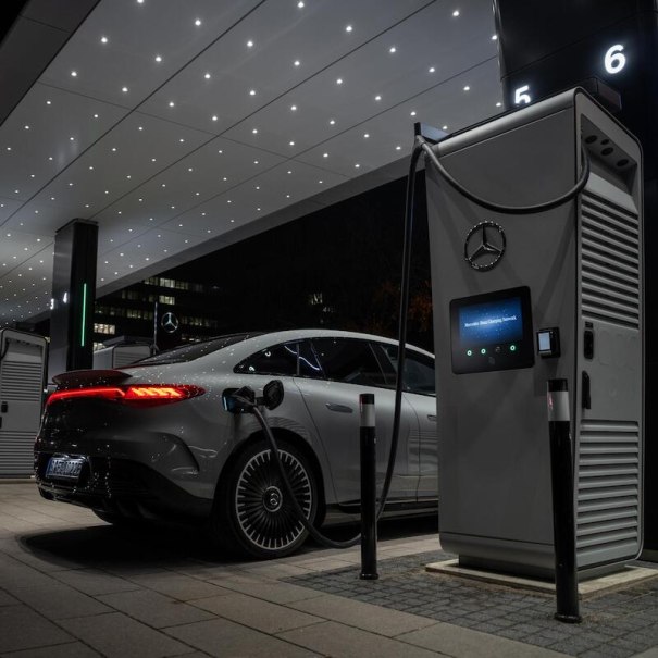 Ein Elektroauto wird nachts an einer modernen Ladestation aufgeladen. Die Umgebung ist beleuchtet und zeigt ein futuristisches Design., &copy; Mercedes-Benz AG