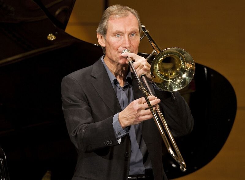 Ein Mann in einem Anzug spielt Posaune auf einer Bühne. Im Hintergrund ist ein Flügel zu sehen. Der Fokus liegt auf dem Musiker und seinem Instrument., © Stadt Böblingen - Amt für Kultur