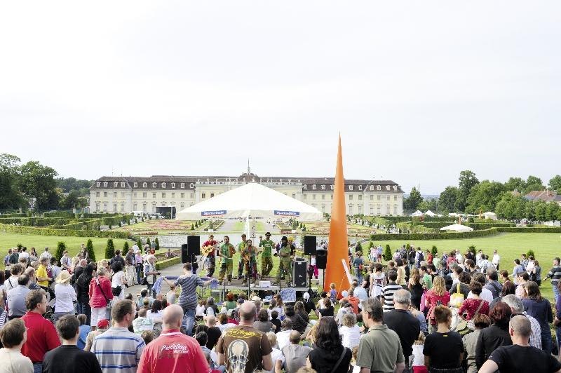 Eine gro&szlig;e Menschenmenge genie&szlig;t ein Stra&szlig;enmusikfestival vor einem historischen Schloss. Eine Band spielt unter einem wei&szlig;en Pavillon., &copy; copyright: Marc Sansone