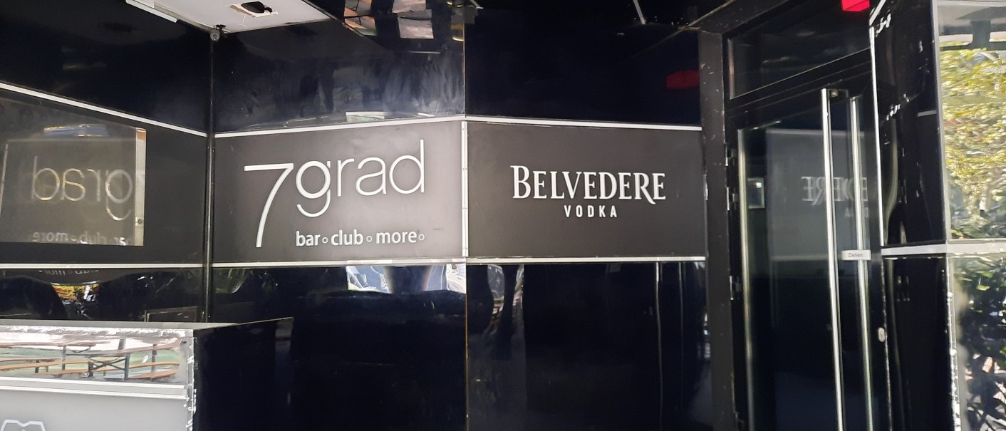 Eingang zur 7grad Bar mit schwarzem Interieur und Belvedere Vodka Werbung. Glastür mit "Ziehen"-Schild sichtbar., © SMG Eingang zur 7grad Bar mit schwarzem Interieur und Belvedere Vodka Werbung. Glastür mit "Ziehen"-Schild sichtbar., © SMG