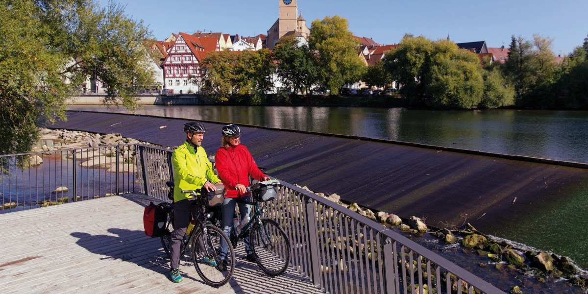 Zwei Radfahrer auf einer Brücke in Nürtingen, im Hintergrund die Altstadt und eine Kirche. Der Fluss fließt ruhig unter der Brücke hindurch., © Stuttgart-Marketing GmbH Zwei Radfahrer auf einer Brücke in Nürtingen, im Hintergrund die Altstadt und eine Kirche. Der Fluss fließt ruhig unter der Brücke hindurch., © Stuttgart-Marketing GmbH