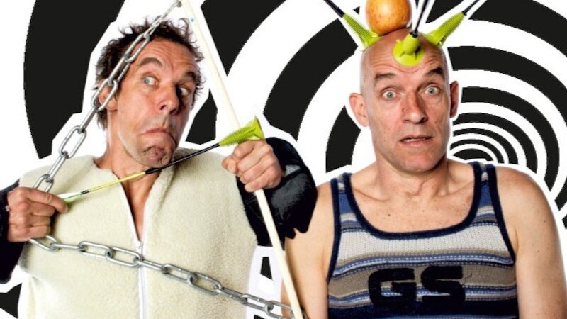 Zwei Männer in lustigen Posen, einer mit Pfeilen und Apfel auf dem Kopf, der andere mit Ketten um den Körper, vor spiralförmigem Hintergrund., © Mauerwerk GmbH