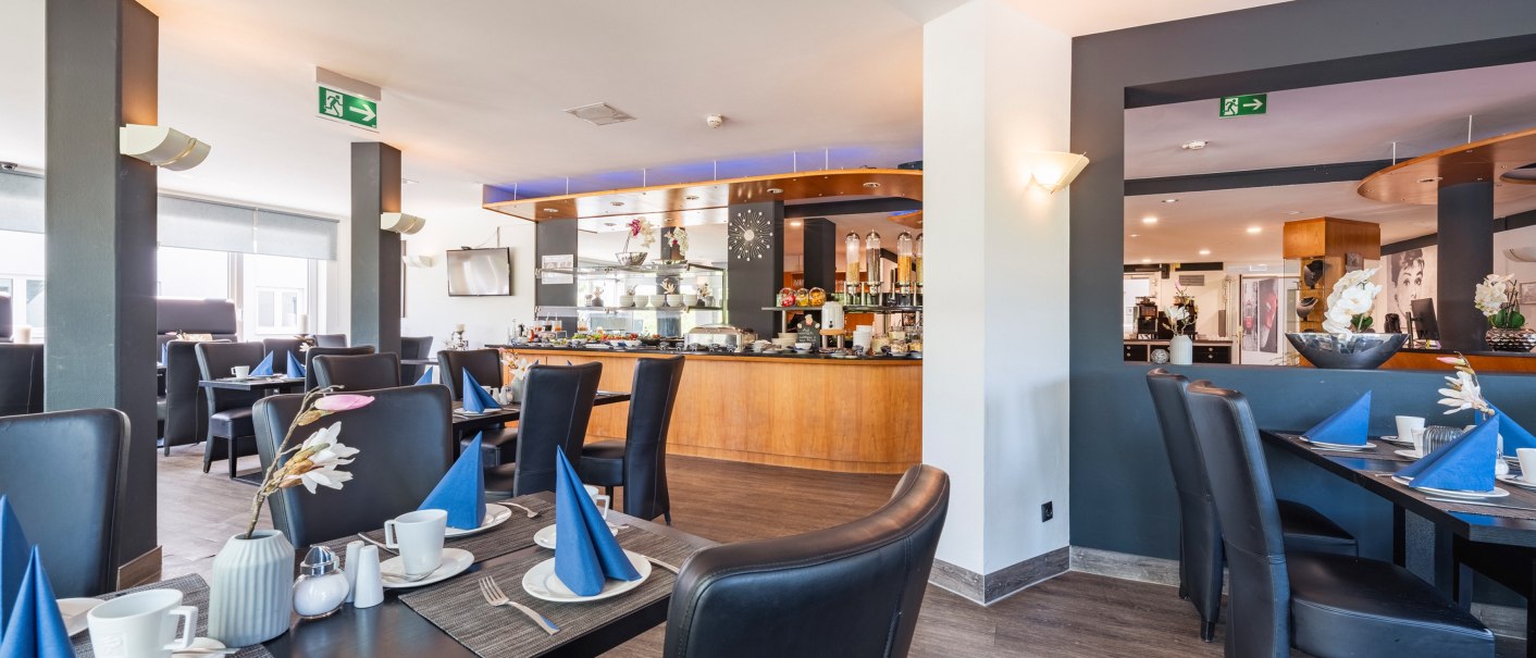 Modernes Restaurant mit eleganten schwarzen Stühlen, gedeckten Tischen und einem Buffetbereich. Dezente Beleuchtung und Dekorationen schaffen eine einladende Atmosphäre., © Plaza INN Stuttgart-Filderstadt Modernes Restaurant mit eleganten schwarzen Stühlen, gedeckten Tischen und einem Buffetbereich. Dezente Beleuchtung und Dekorationen schaffen eine einladende Atmosphäre., © Plaza INN Stuttgart-Filderstadt