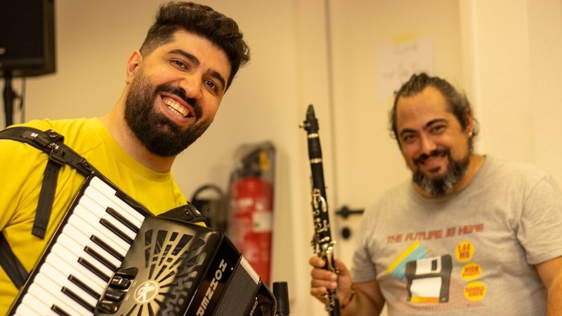 Zwei Musiker l&auml;cheln in die Kamera. Der eine spielt Akkordeon, der andere Klarinette. Sie wirken fr&ouml;hlich und entspannt., &copy; Kulturhaus Schwanen