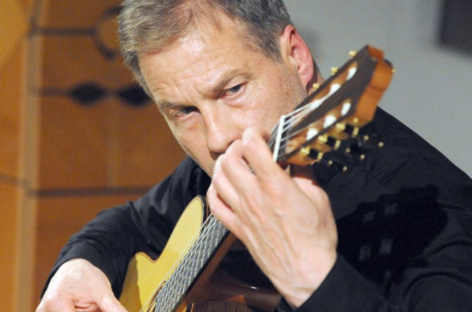 Ein Gitarrist spielt konzentriert auf einer klassischen Gitarre. Er trägt ein schwarzes Hemd und ist in eine musikalische Darbietung vertieft., © Stadt Murrhardt Ein Gitarrist spielt konzentriert auf einer klassischen Gitarre. Er trägt ein schwarzes Hemd und ist in eine musikalische Darbietung vertieft., © Stadt Murrhardt