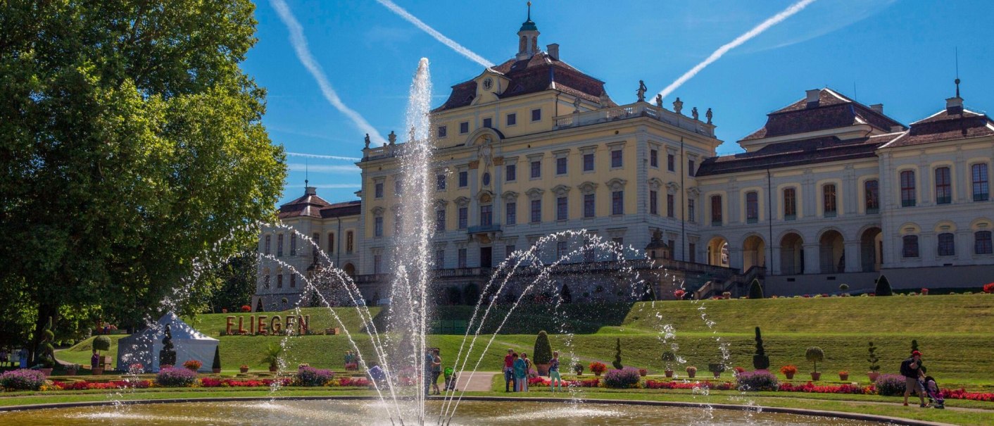 Das Residenzschloss Ludwigsburg mit einem großen Springbrunnen im Vordergrund. Der Himmel ist blau mit Kondensstreifen, umgeben von gepflegten Gärten., © Tourismus & Events Ludwigsburg Das Residenzschloss Ludwigsburg mit einem großen Springbrunnen im Vordergrund. Der Himmel ist blau mit Kondensstreifen, umgeben von gepflegten Gärten., © Tourismus & Events Ludwigsburg