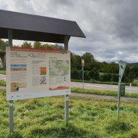 Ein Informationsschild über den Geologischen Pfad von Winnenden nach Grunbach steht neben einer Straße, umgeben von grüner Landschaft., © Stadtverwaltung Winnenden
