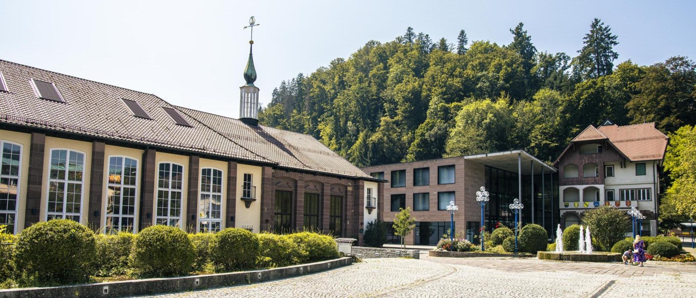 Historische Gebäude in Bad Liebenzell mit modernem Anbau, umgeben von Bäumen und einem gepflasterten Platz mit Brunnen., © Stuttgart-Marketing GmbH, Sarah Schmid