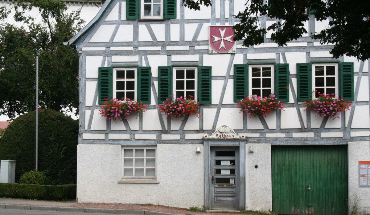 Fachwerkhaus mit grünen Fensterläden, blühenden Blumenkästen und einem Schild mit der Aufschrift 'Rathaus'. Ein Wappen ist über der Tür sichtbar., © Natur.Nah. Schönbuch & Heckengäu
