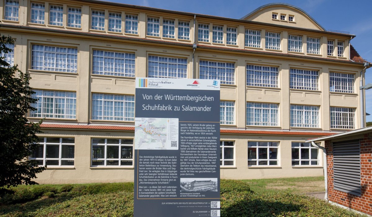 Ein historisches Gebäude mit großen Fenstern und einer Infotafel zur Geschichte der Württembergischen Schuhfabrik Salamander., © Stoppel