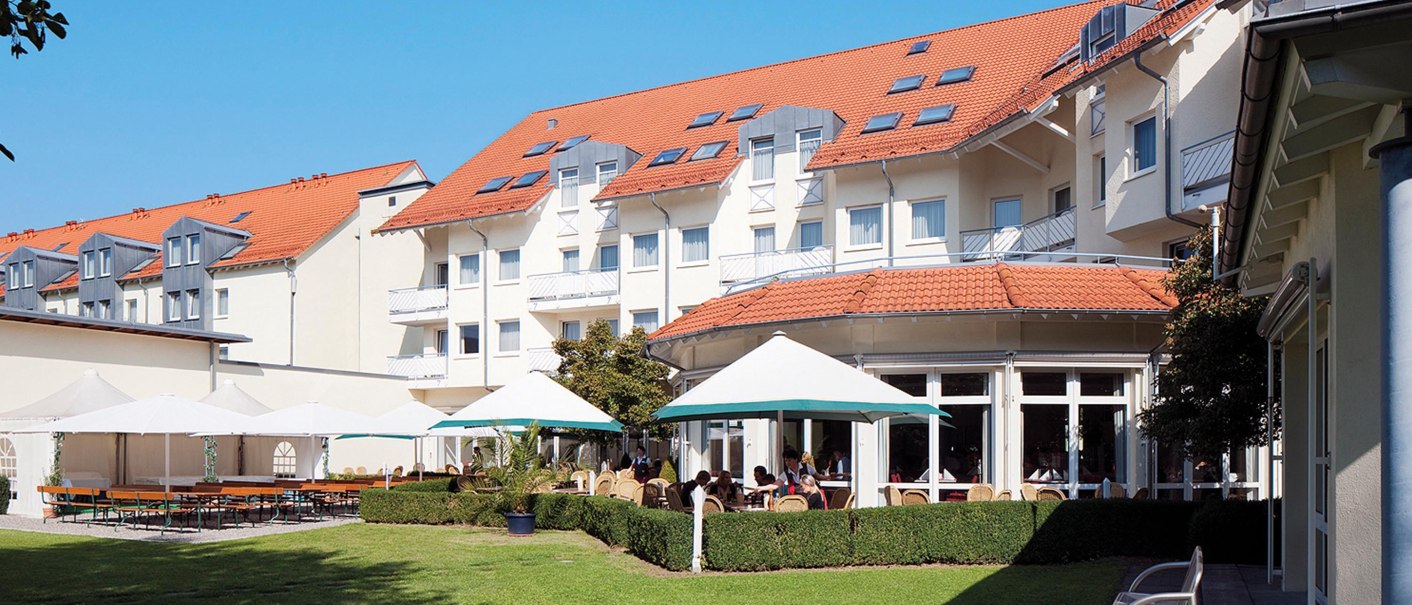 Hotel mit rotem Dach, Terrasse mit Sonnenschirmen und Sitzgelegenheiten im Garten. Sonniger Tag, blauer Himmel., © Seminaris Hotel Bad Boll Hotel mit rotem Dach, Terrasse mit Sonnenschirmen und Sitzgelegenheiten im Garten. Sonniger Tag, blauer Himmel., © Seminaris Hotel Bad Boll
