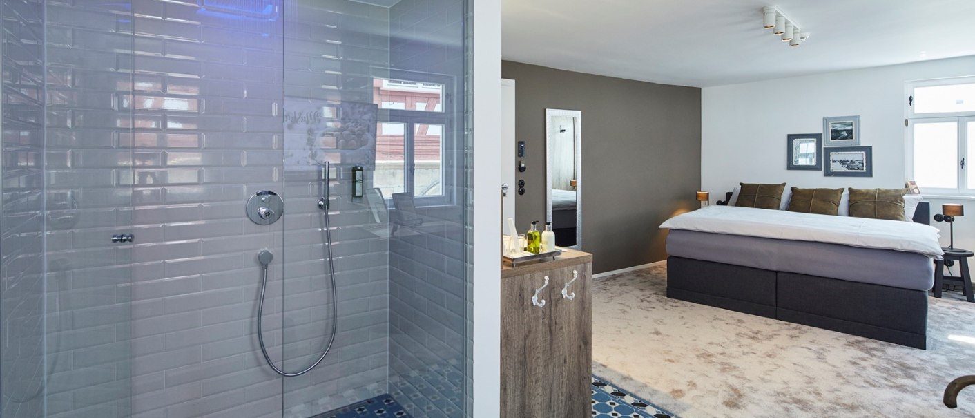 Modernes Zimmer mit offener Dusche, blauer Beleuchtung, Doppelbett und stilvollen Dekorationen. Teppichboden und Fliesen im Duschbereich., © Hotel Restaurant Bachofer Modernes Zimmer mit offener Dusche, blauer Beleuchtung, Doppelbett und stilvollen Dekorationen. Teppichboden und Fliesen im Duschbereich., © Hotel Restaurant Bachofer