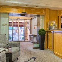 Empfangsbereich mit Holzmöbeln, Sitzgelegenheiten und Glastür. Einladende Atmosphäre mit Pflanzen und Dekoration., © Centro Hotels