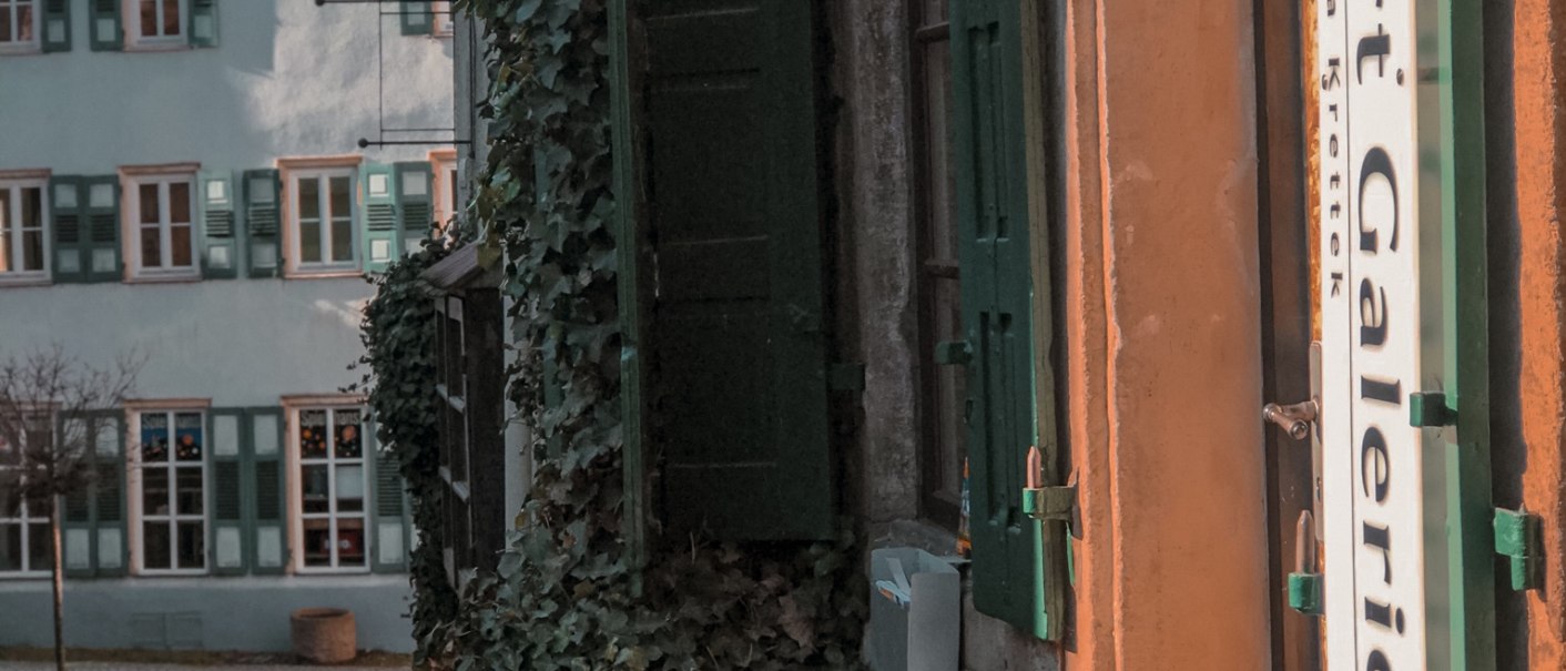 Altstadtgasse in N&uuml;rtingen mit Efeu-bewachsenem Geb&auml;ude, gr&uuml;nen Fensterl&auml;den und kleinem Dreirad vor einer Galerie., &copy; Martina Naumov