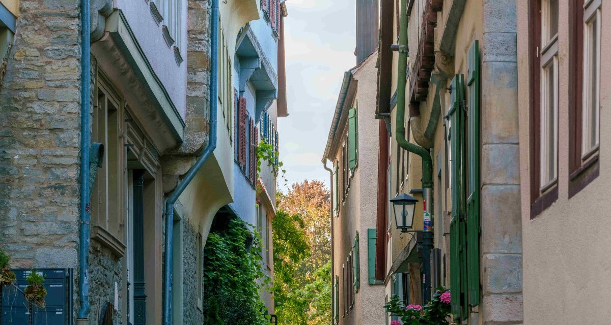 Schmale Gasse in Schw&auml;bisch Hall mit Fachwerkh&auml;usern, Kopfsteinpflaster und bl&uuml;henden Pflanzen in T&ouml;pfen. Historische Architektur und ruhige Atmosph&auml;re., &copy; Michael K&uuml;hneisen