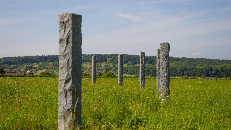 Mehrere Steinsäulen stehen in einer grünen Wiese, umgeben von Hügeln und Wald im Hintergrund unter einem blauen Himmel., © Remstal Tourismus e.V. Mehrere Steinsäulen stehen in einer grünen Wiese, umgeben von Hügeln und Wald im Hintergrund unter einem blauen Himmel., © Remstal Tourismus e.V.