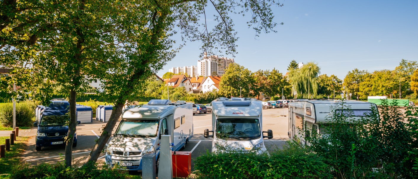 Wohnmobilstellplatz in Leonberg mit geparkten Wohnmobilen, umgeben von Bäumen und Gebäuden im Hintergrund bei klarem Himmel., © Stuttgart-Marketing GmbH, Thomas Niedermüller Wohnmobilstellplatz in Leonberg mit geparkten Wohnmobilen, umgeben von Bäumen und Gebäuden im Hintergrund bei klarem Himmel., © Stuttgart-Marketing GmbH, Thomas Niedermüller