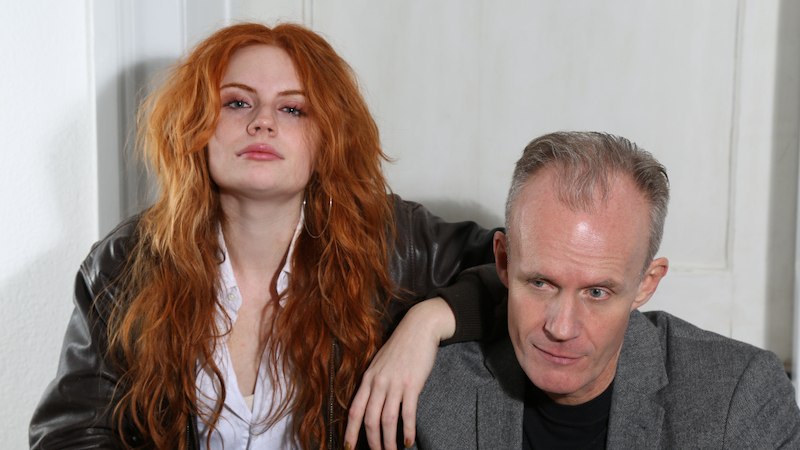 Eine Frau mit roten Haaren und ein Mann in einem grauen Blazer sitzen nebeneinander. Die Frau tr&auml;gt eine Lederjacke, der Mann schaut nachdenklich., &copy; Konzertkreis Triangel Compagnia Compostelli e.V.