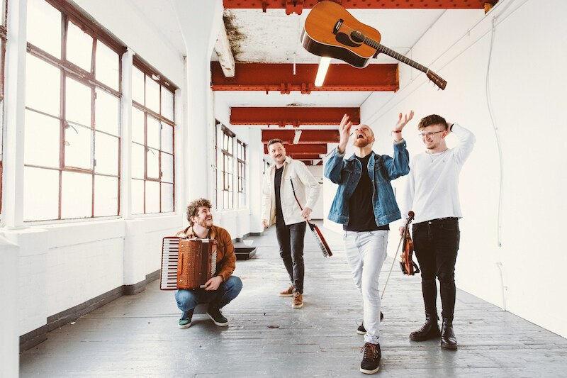 Vier M&auml;nner in einem hellen Raum, einer wirft eine Gitarre in die Luft. Die anderen halten Instrumente und l&auml;cheln. Der Raum hat gro&szlig;e Fenster und rote Deckenbalken., &copy; Stadt Leinfelden-Echterdingen, Kulturamt