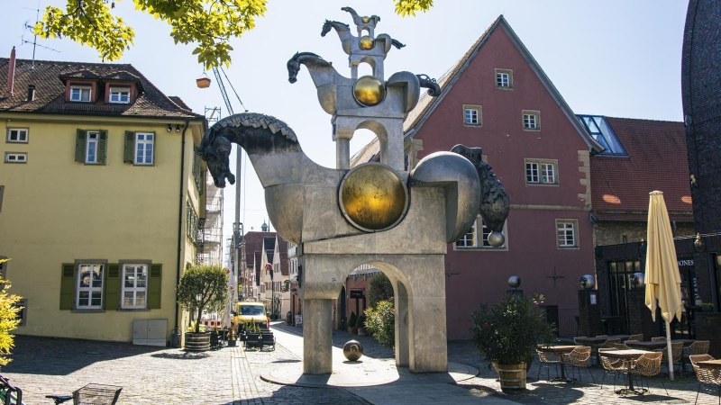 Skulptur der Grauen Pferde in Bietigheim-Bissingen, umgeben von historischen Gebäuden und einem Café mit Tischen und Stühlen im Freien., © Stuttgart Marketing GmbH, Sarah Schmid Skulptur der Grauen Pferde in Bietigheim-Bissingen, umgeben von historischen Gebäuden und einem Café mit Tischen und Stühlen im Freien., © Stuttgart Marketing GmbH, Sarah Schmid