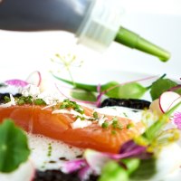Ein Gourmetgericht mit Lachs, essbaren Blumen und grüner Sauce auf einem weißen Teller, kunstvoll angerichtet., © Stuttgart-Marketing GmbH, Annette Sandner Ein Gourmetgericht mit Lachs, essbaren Blumen und grüner Sauce auf einem weißen Teller, kunstvoll angerichtet., © Stuttgart-Marketing GmbH, Annette Sandner