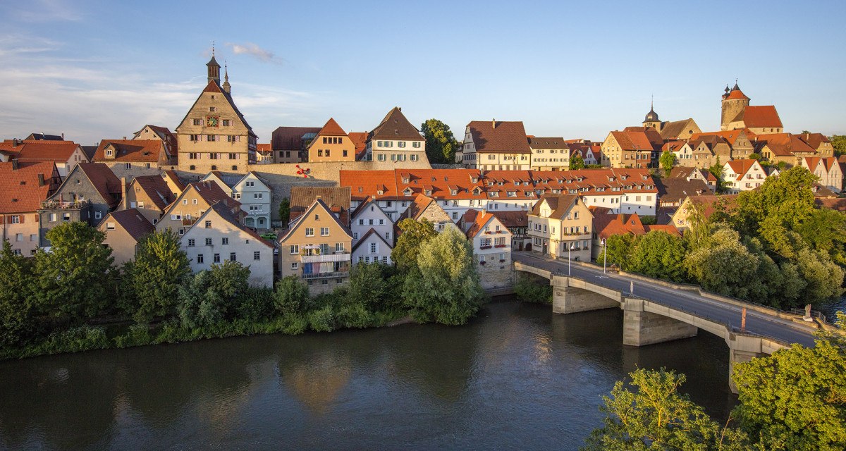 Die Altstadt von Besigheim mit ihren historischen Gebäuden und roten Dächern, umgeben von einem Fluss und einer Brücke im Vordergrund., © Unbekannt