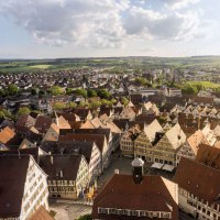 Panorama einer Stadt mit vielen Fachwerkhäusern, umgeben von grüner Landschaft und Feldern unter einem bewölkten Himmel., © Martina Denker