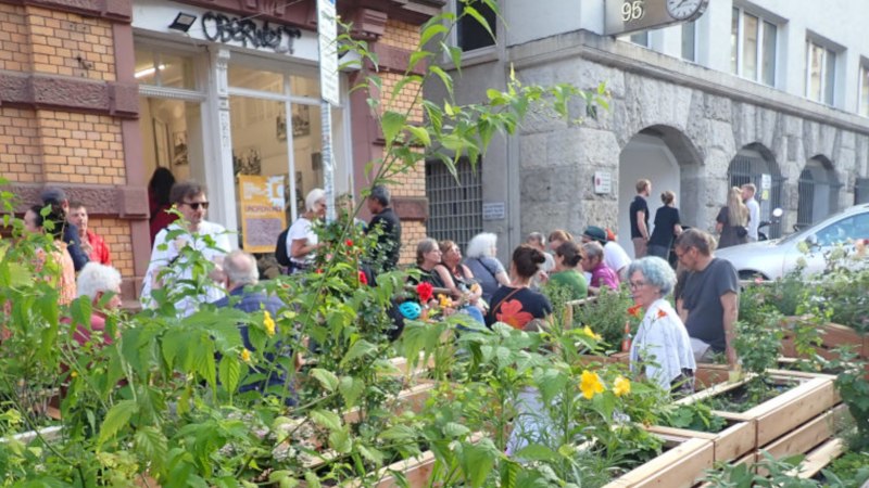 Menschen genie&szlig;en einen urbanen Garten vor einem Geb&auml;ude mit der Aufschrift 'Oberwelt'. Es herrscht eine entspannte Atmosph&auml;re., &copy; Oberwelt e.V.