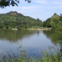 Ein See mit ruhigem Wasser, umgeben von gr&uuml;nen H&uuml;geln und B&auml;umen. Menschen entspannen am Ufer., &copy; Remstal Tourismus e.V.