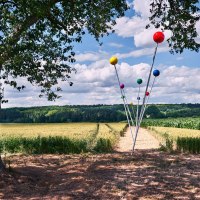 Kunstinstallation mit bunten Kugeln auf Stangen in einem Feld. Ein Baum spendet Schatten, der Himmel ist bewölkt. Der Titel lautet 'Der 9. Meridian'., © Natur.Nah. Schönbuch & Heckengäu Kunstinstallation mit bunten Kugeln auf Stangen in einem Feld. Ein Baum spendet Schatten, der Himmel ist bewölkt. Der Titel lautet 'Der 9. Meridian'., © Natur.Nah. Schönbuch & Heckengäu