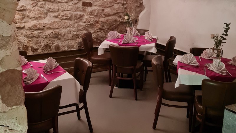 Ein gem&uuml;tlicher Kellerraum mit Steinw&auml;nden und gew&ouml;lbter Decke. Die Tische sind mit wei&szlig;en Tischdecken und roten Servietten dekoriert., &copy; DaInes